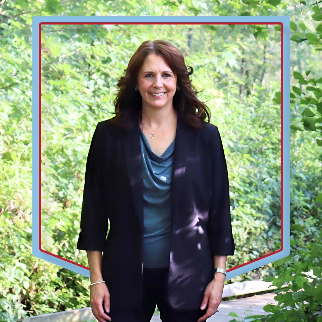 Melanie Summers poses with a wooded background.